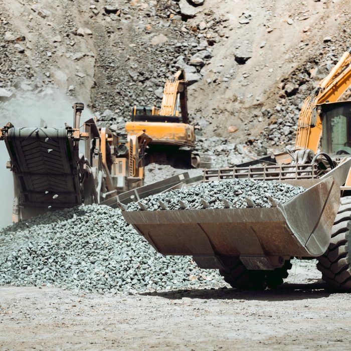 Large wheel loader on construction site transporting and loading gravel into dumper trucks