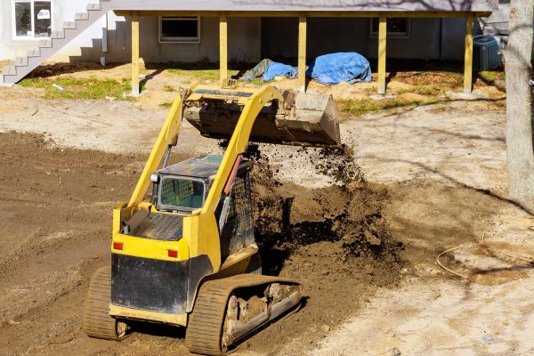 Mini bulldozer landscaping works on construction working with earth while doing scoop excavator